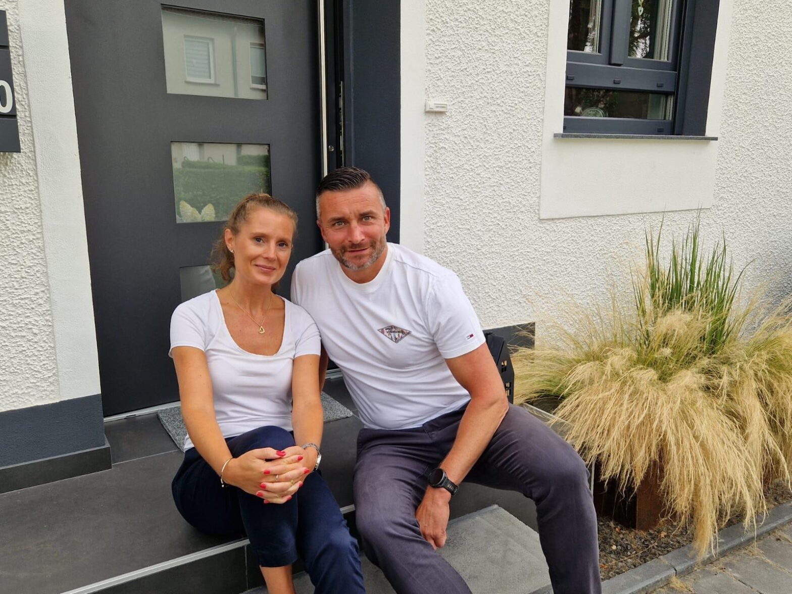 Frau und Mann sitzen vor ihrer Immobilie